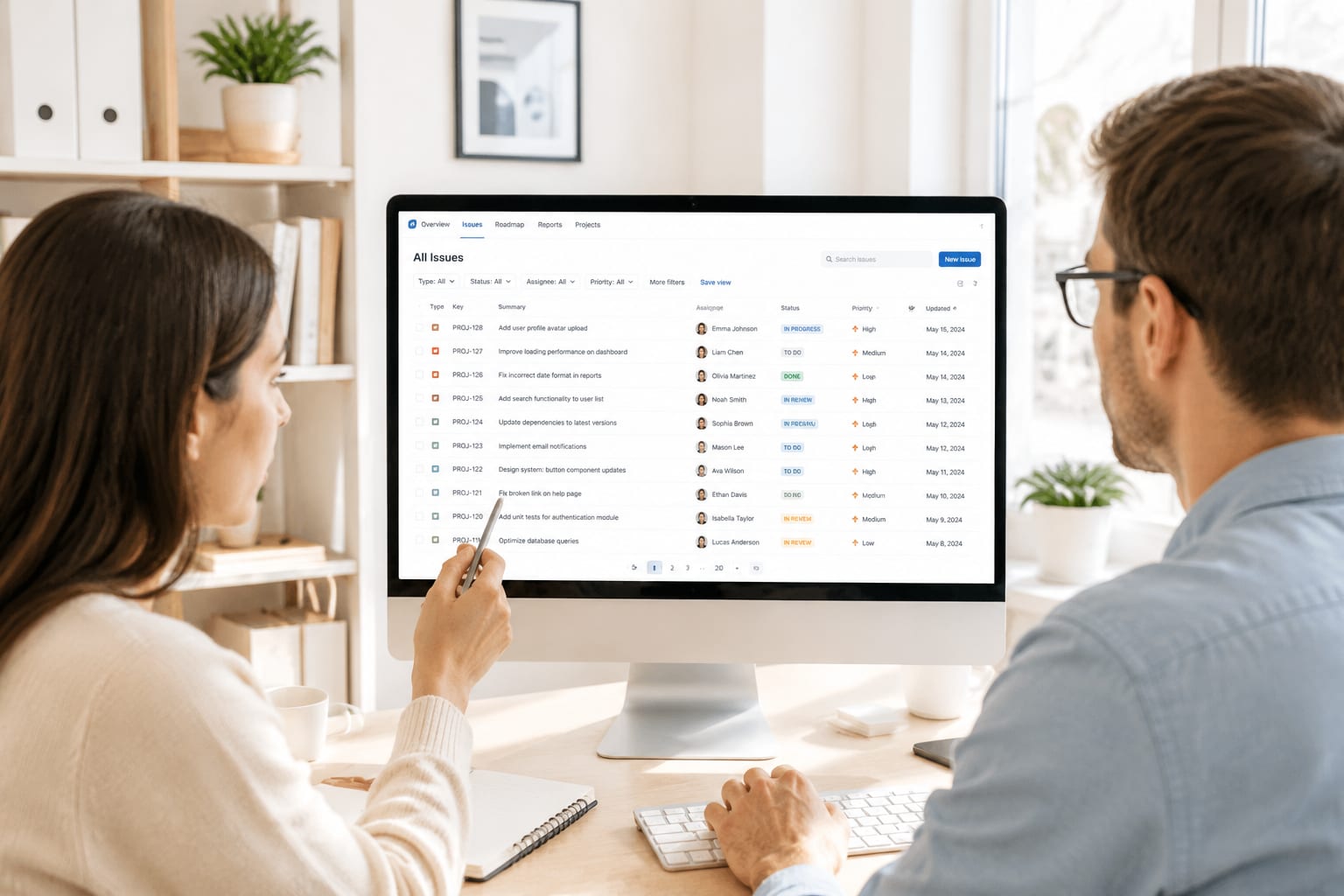 Product team reviewing a light-themed issue tracking interface on a large monitor